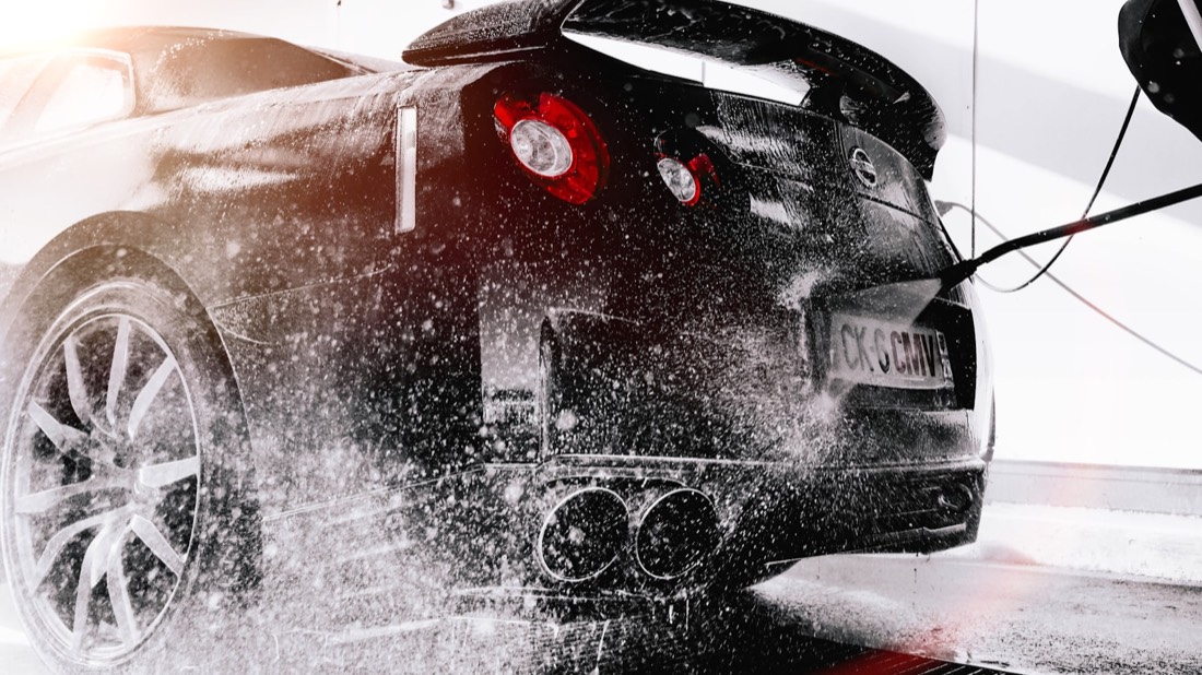 High-pressure rinse on a black sports car during an ICON exterior detail